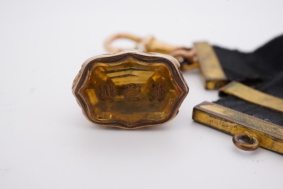 A late Victorian yellow metal overlaid and citrine set watch key fob, depicting two horses and two rams?, 30mm on a black sash suspension, together with a modern pair of 9ct gold and cultured pearl set leaf ear studs. Co